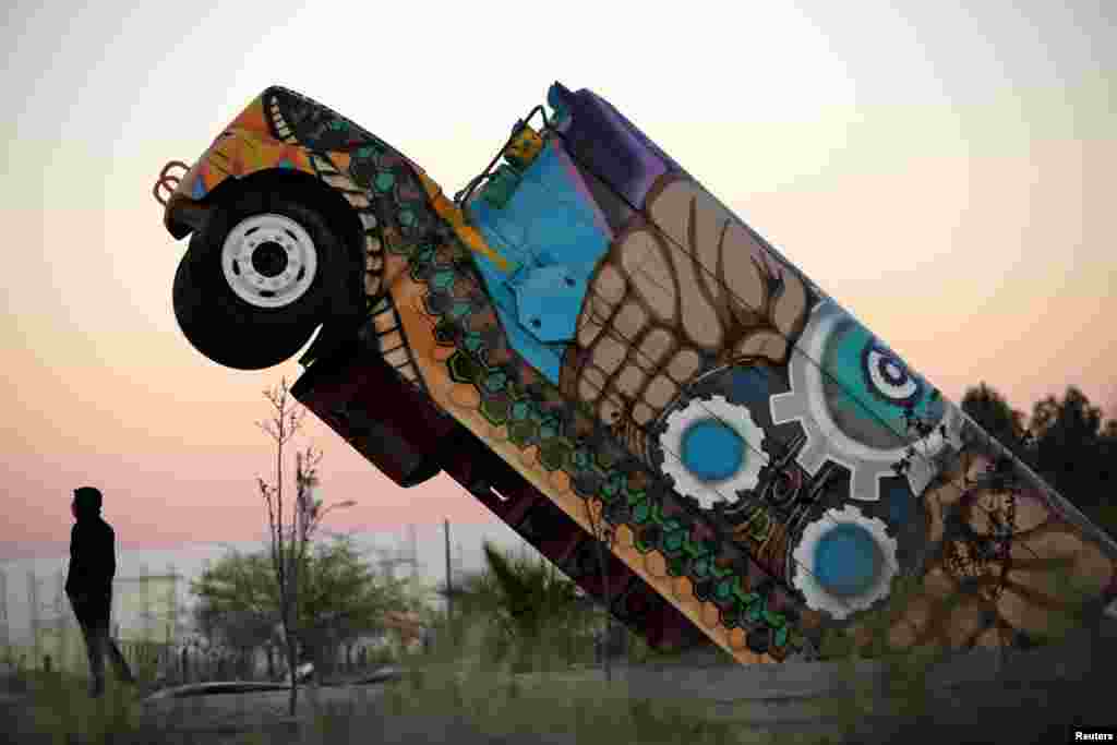 A man stands next to the 'Ser Fronterizo' monument, a retired U.S. school bus cut in half and erected to recognize the employees of assembly factories who use public transportation daily to get to work, in Ciudad Juarez, Mexico, March 14, 2019.