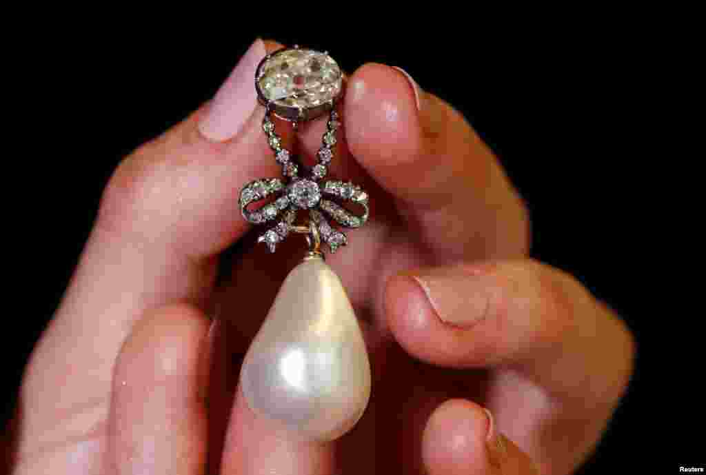 A natural pearl and diamond pendant once owned by Marie Antoinette is held by a model during a press preview ahead of the upcoming auction "Royal jewels from the Bourbon Parma Family" at Sotheby's in Geneva, Switzerland.