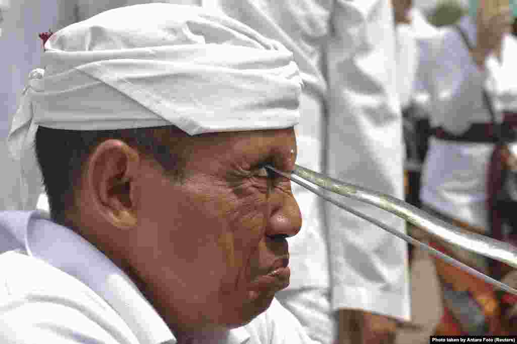 A Balinese Hindu worshiper attempts to stab himself with traditional Kris daggers while in trance during Melasti, a purification ceremony ahead of the holy day of Nyepi, at Petitenget beach in Bali, Indonesia.