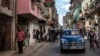 ARCHIVO - La gente camina bajo un cartel que anuncia una tienda de comestibles privada, a la izquierda, en La Habana, el 11 de noviembre de 2023. 
