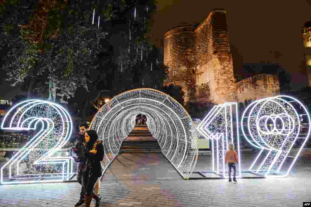 People walk past a "2019" new year decorations in front of the Maiden Tower in the Old city in central Baku, Azerbaijan, Dec. 22, 2018.