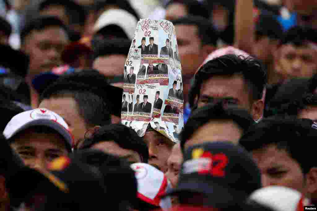 A supporter wears a hat made of pictures of Indonesia's presidential candidate for next month's election Prabowo Subianto and his running mate Sandiaga Uno, during a campaign rally in Bogor, West Java province.