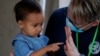 El voluntario Mark McDonald, a la derecha, trabaja con un niño inmigrante en una clínica habilitada para solicitantes de asilo que esperan en Matamoros, México, el jueves 19 de noviembre de 2020.