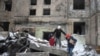ARCHIVO - Personas salen con sus pertenencias de un edificio de apartamentos destruido después del ataque ruso del martes en Kiev, Ucrania, el 3 de enero de 2024.