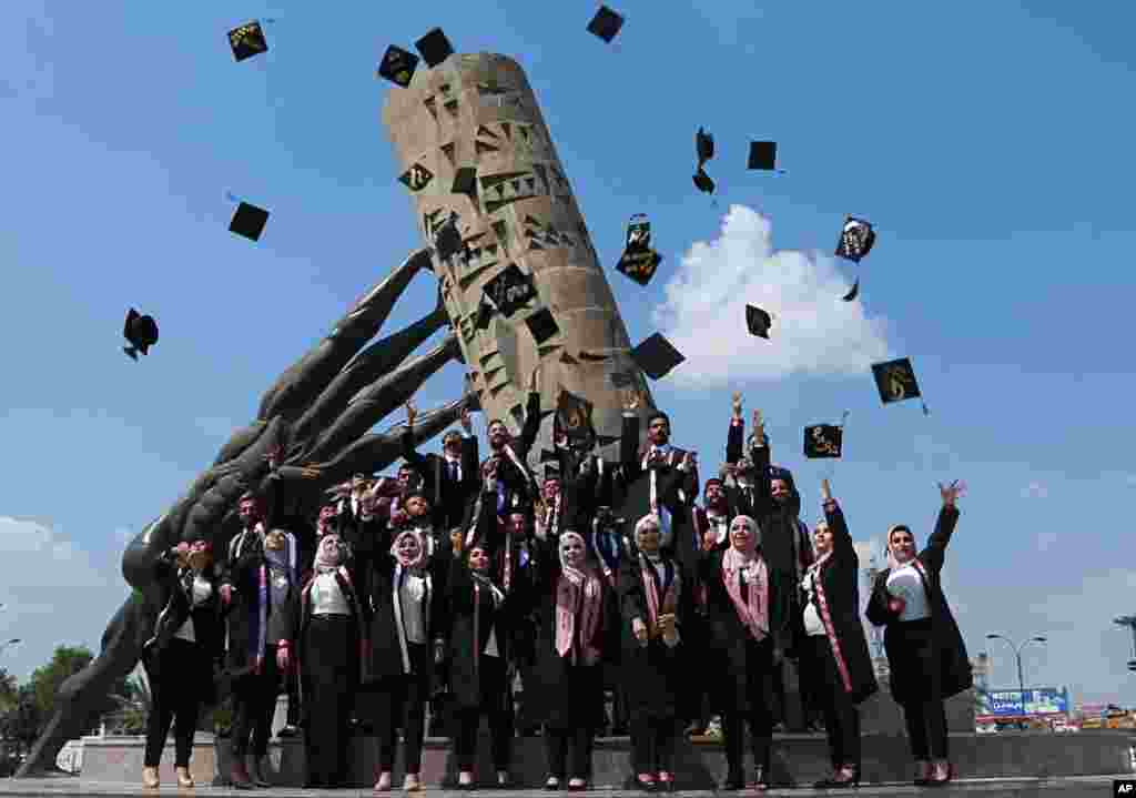 University of Baghdad graduates throw their caps in the air while posing for a group photo next to the 'save Iraqi culture' monument, in Baghdad.