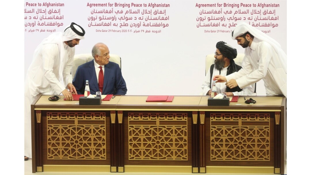 FILE - In this Feb. 29, 2020 file photo, U.S. peace envoy Zalmay Khalilzad, left, and Mullah Abdul Ghani Baradar, the Taliban group's top political leader sign a peace agreement between Taliban and U.S. officials in Doha, Qatar.