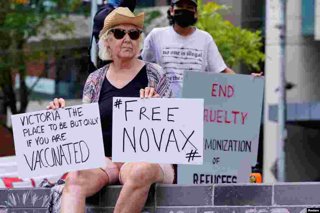 A protester holds signs outside the Park Hotel, where Serbian tennis player Novak Djokovic is believed to be held, in Melbourne, Australia. Novak Djokovic faced at least 72 hours holed up in a Melbourne hotel for immigration detainees after he was denied entry into Australia amid a political firestorm over his medical exemption from COVID-19 vaccination requirements.