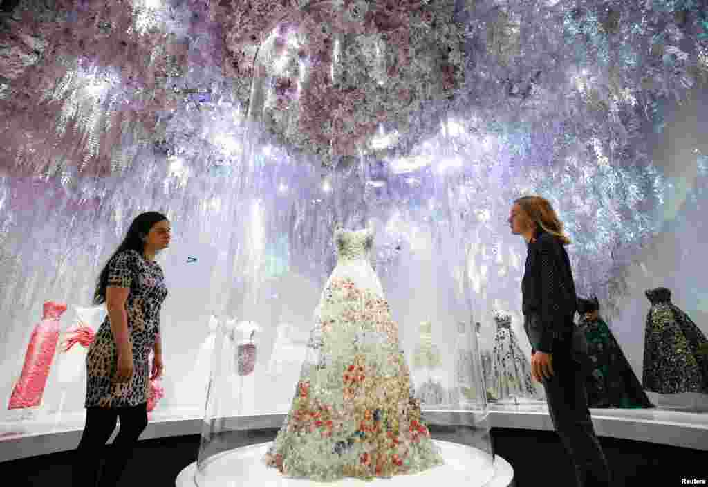 Gallery assistants pose for members of the media during a photocall for the "Christian Dior: Designer of Dreams" exhibition at the Victoria & Albert (V&A) Museum in London.
