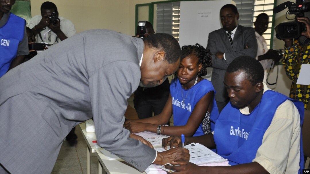 Burkina Faso incumbent President Blaise Compaore signs document after casting ballot at polling station during legislative, municipal elections, Ouagadougou, Dec. 2, 2012.