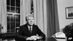 FILE - Umongameli Jimmy Carter ehlezi esihlalweni sikamongameli ngomnyaka ka 1977