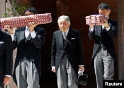 FILE - Japan's Emperor Akihito, flanked by Imperial Household Agency officials carrying two of the so-called Three Sacred Treasures of Japan, leaves the main sanctuary as he visits the Inner shrine of the Ise Jingu shrine, ahead of his April 30, 2019 abdication.