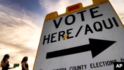 ARCHIVO - Dos votantes entregan su papeleta en una casilla electoral, el 3 de noviembre de 2020, en Tempe, Arizona.