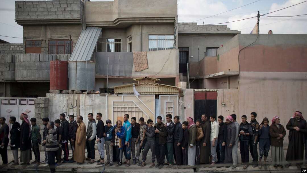 Iraqi civilians line up to receive food supplies in a neighborhood recently liberated by Iraqi security forces in western Mosul, March 14, 2017.