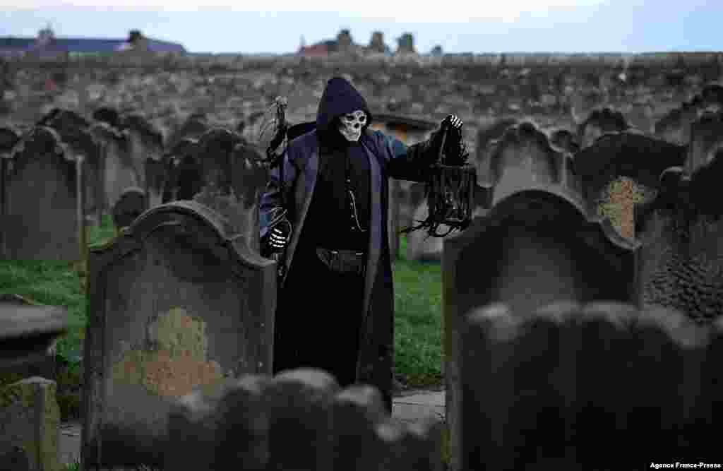 A participant in costume stands amongst gravestones at St. Mary the Virgin's church during the biannual 'Whitby Goth Weekend' festival in Whitby, northern England.
