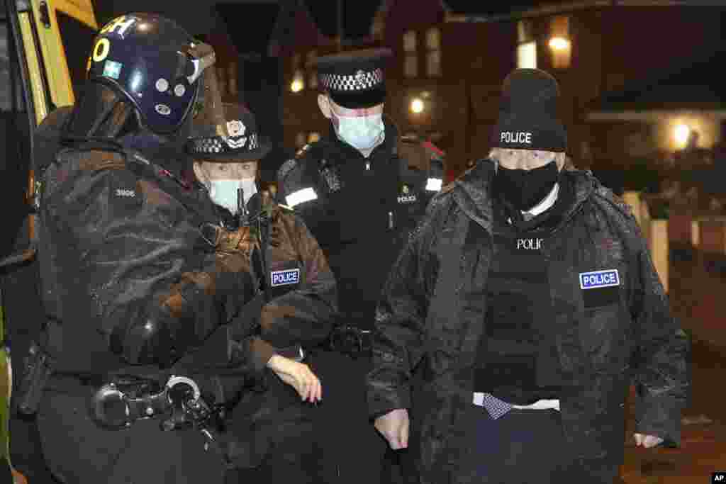 Britain's Prime Minister Boris Johnson, right, observes an early morning police raid on a home in Liverpool, England, ahead of the publication of the government's 10-year drug strategy.