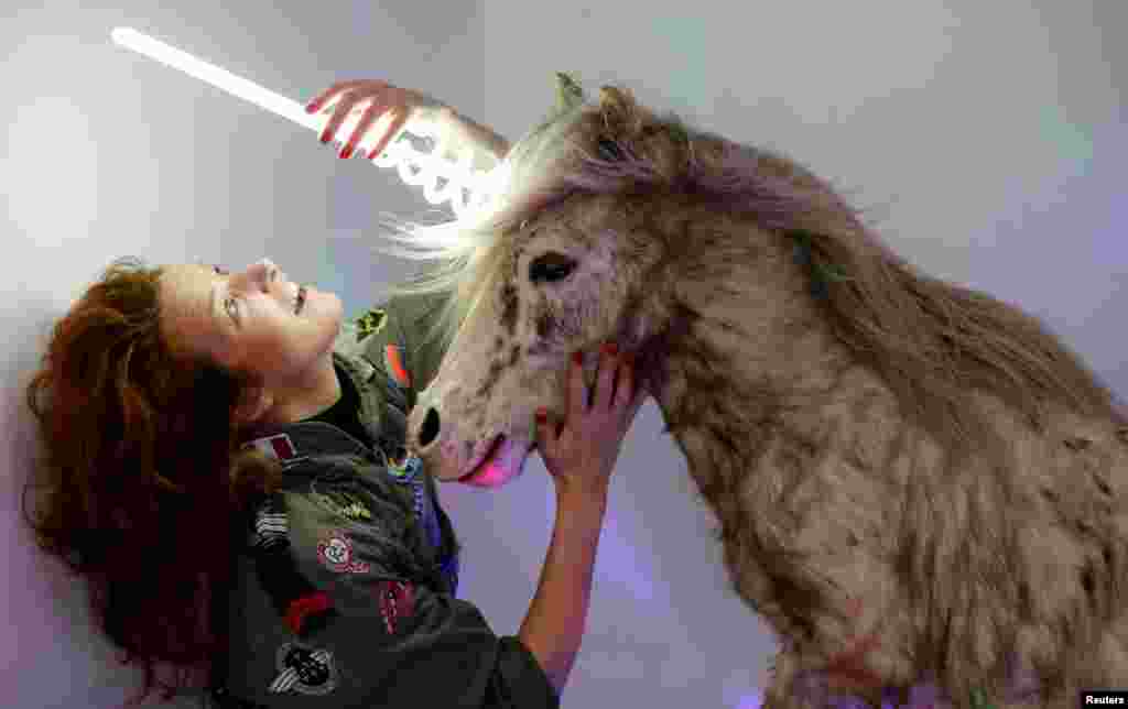 Artist and naturalist Stephanie Barthes adjusts a neon lamp on a stuffed pony as she works on her art creation called "Poney-Licorne" at her workshop in Bordeaux, France.