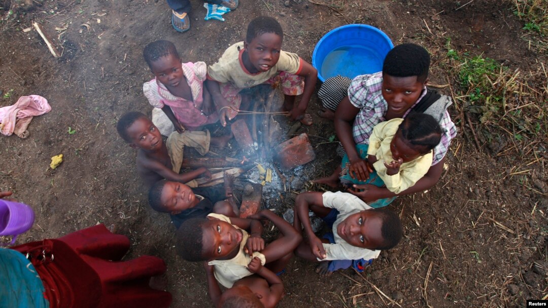 FILE - A Congolese refugee family displaced by fighting between the Congo army and a rebel group, Allied Democratic Forces (ADF), warm themselves around fire at Bukanga transit camp in Bundibugyo, Uganda, July 2013.