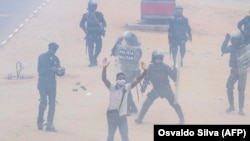 Manifestante põe as mãos no ar, enquanto se afasta da polícia, durante manifestação anti-governo em Luanda, 24 outubro 2020