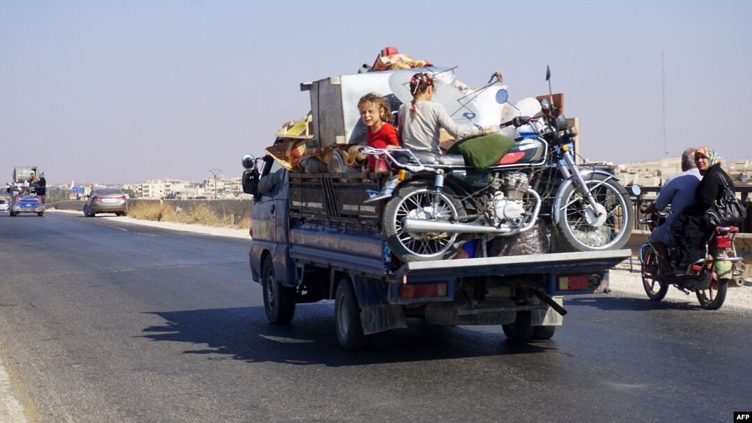 Syrian children ride in the back of a truck loaded with furniture and a motorcycle, driving along the main Damascus-Aleppo highway near the town of Saraqib in Syria's mostly rebel-held northern Idlib province, as families flee north from the countryside, Sept. 11, 2018. 