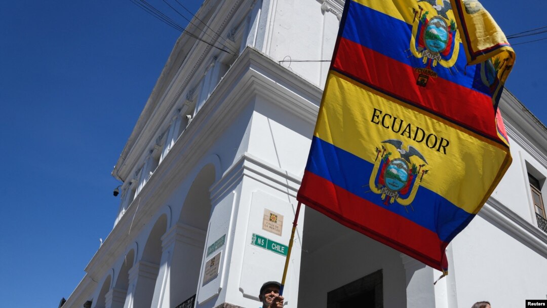 Un hombre ondea las banderas nacionales de Ecuador frente al palacio presidencial después de que el presidente Guillermo Lasso, disolviera la Asamblea Nacional por decreto el 17 de mayo de 2023.
