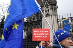 FILE - Anti-Brexit demonstrators hold signs outside the Houses of Parliament in London, Britain, Dec. 17, 2019.