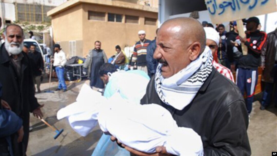 A Libyan man carries away partial remains of a man's body at Al-Jalaa hospital in Benghazi, February 21, 2011