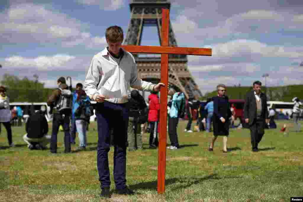 A pilgrim holds a cross as he attends the annual Good Friday "Stations of the Cross" procession at the Champs de Mars near the Eiffel Tower in Paris, April 18, 2014. 