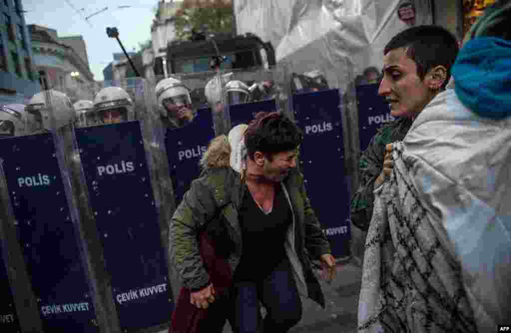 Protesters react after Turkish anti-riot police used tear gas against women's rights activists who try to march to Taksim Square to protest against gender violence in Istanbul on the International Day for the Elimination of Violence Against Women.