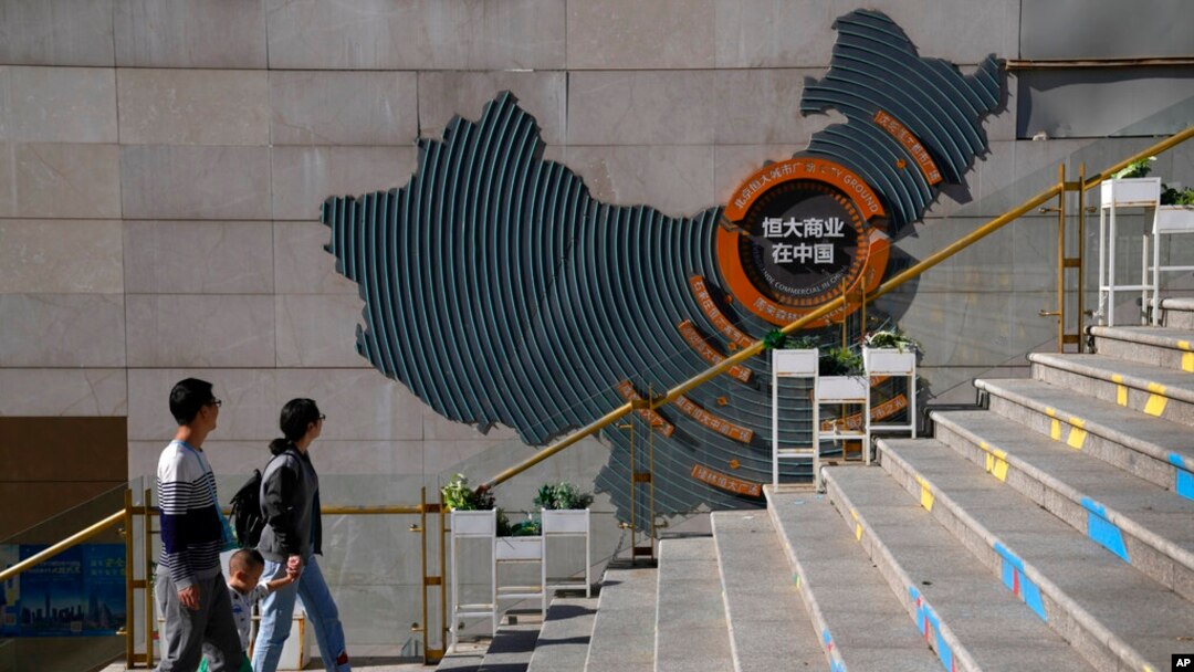 A family walks by a map showing Evergrande development projects in China at an Evergrande city plaza in Beijing, Sept. 21, 2021.(AP Photo/Andy Wong)
