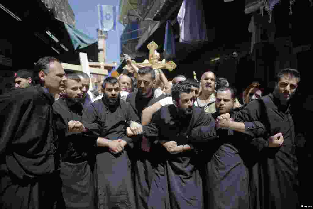 Christian worshippers lock arms during a procession along the Via Dolorosa on Good Friday during Holy Week in Jerusalem's Old City, April 18, 2014. 
