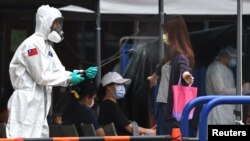 一名台灣士兵向一名離開台北新冠病毒檢測中心的女子身上噴灑消毒藥水。（2021年5月18日）