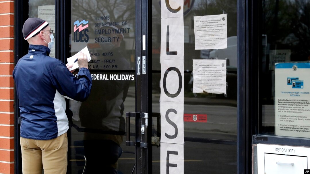 FILE - In this April 30, 2020 file photo, a man writes information in front of Illinois Department of Employment Security in Chicago. 