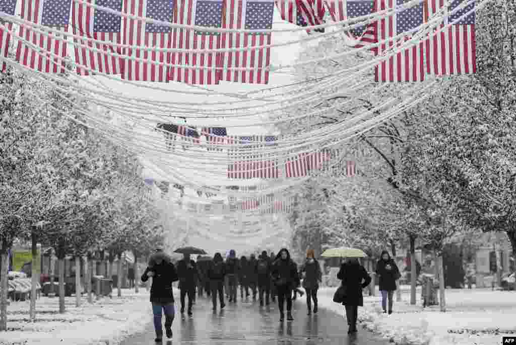 Pedestrians walk under United States flags displayed at the Mother Teresa square in Pristina, Kosovo.