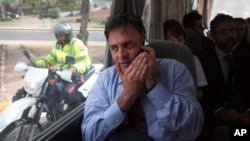 El senador brasileño Aécio Neves habla en su celular desde el microbus en el que intentaron visitar a los lideres opositores venezolanos presos.