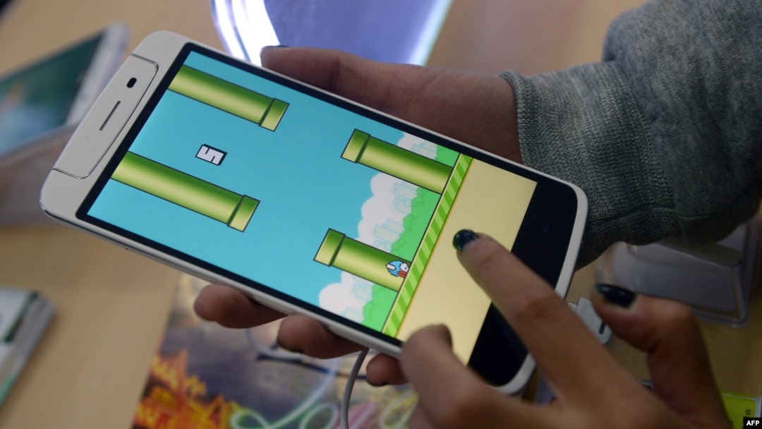 An employee plays the game Flappy Bird at a smartphone store in Hanoi, Feb. 10, 2014. (AFP PHOTO/HOANG DINH Nam)