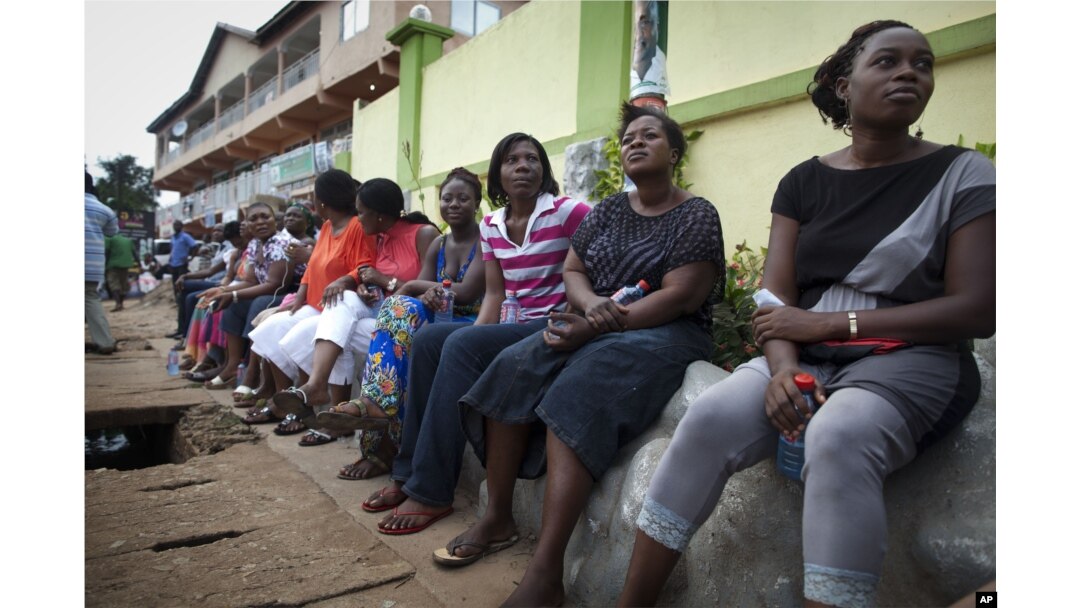 FILE - Voters wait three hours after biometric identification machines had broken down, halting voting at a polling station, in Accra, Ghana, Dec. 7, 2012.