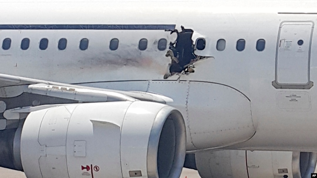 A gaping hole is visible in the side of a plane operated by Daallo Airlines as it sits on the runway of the airport in Mogadishu, Somalia, Feb. 2, 2016. 