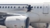 FILE - A gaping hole is visible in the side of a plane operated by Daallo Airlines as it sits on the runway of the airport in Mogadishu, Somalia, Feb. 2, 2016. 