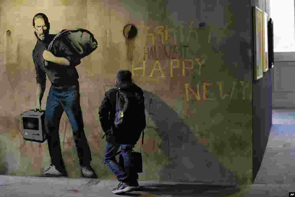 A visitor looks at "Steve Jobs", a reproduction of a mural by British artist Banksy, during the unveiling of the "The World of Banksy, The Immersive Experience" exhibition, in Milan, Italy.