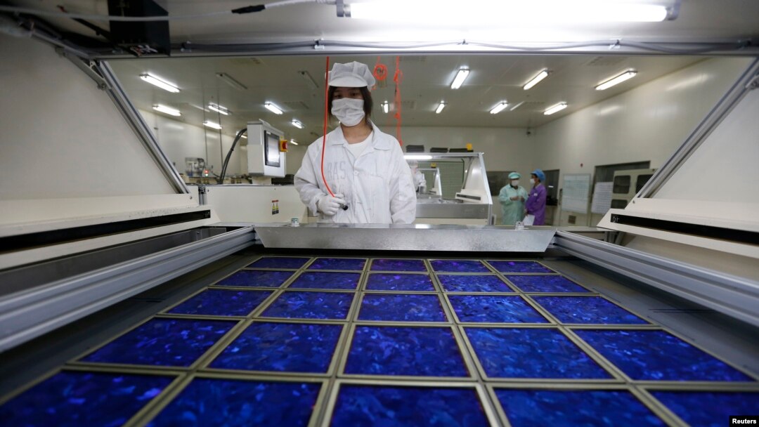 An employee dries newly made solar panels at a factory of a photovoltaic company in Jiaxing, Zhejiang province, June 5, 2013.