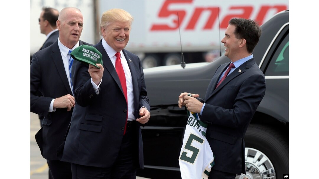 FILE - Wisconsin Gov. Scott Walker, right, presents President Donald Trump with a Milwaukee Buck basketball hat and jersey as he arrives in Kenosha, Wisconsin, April 18, 2017.