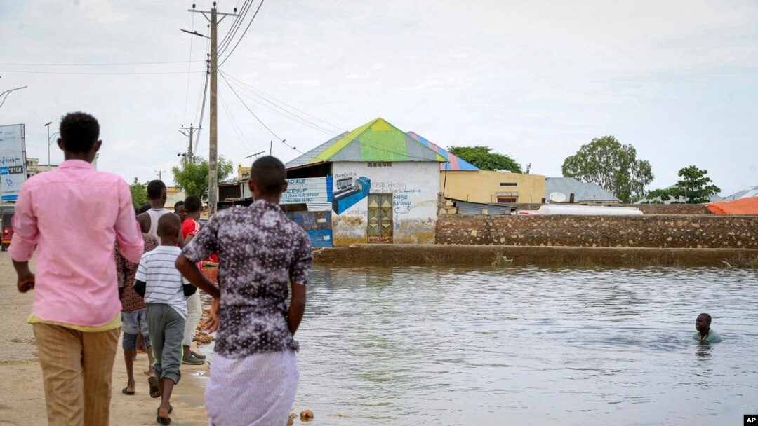 A child swims in the floodwaters as others walk past in the town of Beledweyne, in central Somalia, Nov. 4, 2019. Authorities have not yet said how many people died in Somalia's recent flooding, the country's worst in recent history.