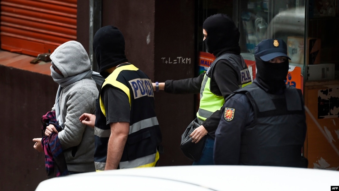 Spanish police arrest a man, left, accused of collaborating with the Islamic State, after searching a cybercafe in Mataro near to Barcelona, Dec. 8, 2015. 