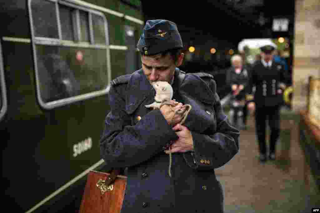 A wartime reenactor cuddles a ferret as they prepare to board a train during a reenactment-themed weekend, the annual 'Railway in Wartime' event held along the North Yorkshire Moors Railway, in Pickering, northern England.