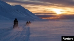 FILE - Scientists drive their snowmobiles cross the arctic towards Kongsfjord during sunset near Ny-Alesund, Svalbard, Norway, April 10, 2023. 