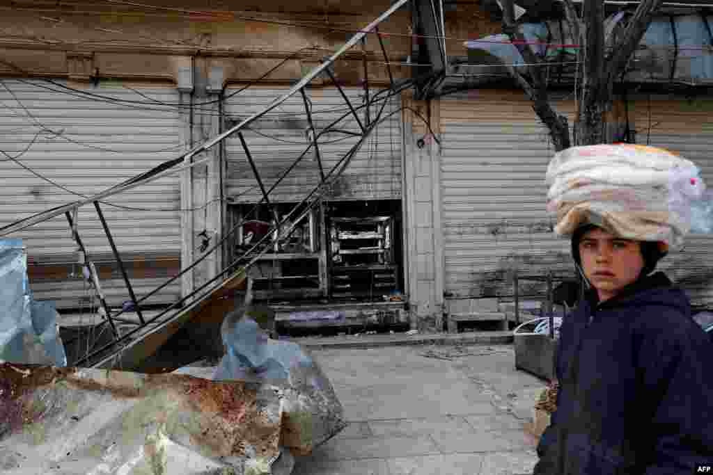 A boy walks past the shuttered doors of a restaurant that was the site of a suicide attack targeting US-led coalition forces in the flashpoint northern Syrian city of Manbij. which killed four US servicemen the previous day.