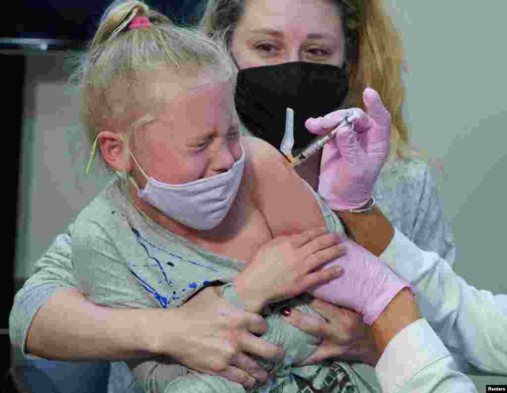 Emma Ingle, 7, sitting on her mother Kim Obert's lap, receives her first dose of the Pfizer-BioNTech coronavirus vaccine in Storrs, Connecticut, Nov. 3, 2021.