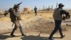 Iraqi forces walk past an oil production plant as they head towards the city of Kirkuk during an operation against Kurdish fighters on Oct. 16, 2017. 