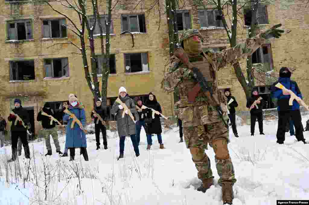 A military instructor teaches civilians holding wooden replicas of Kalashnikov rifles, during a training session at an abandoned factory in the Ukrainian capital of Kyiv.