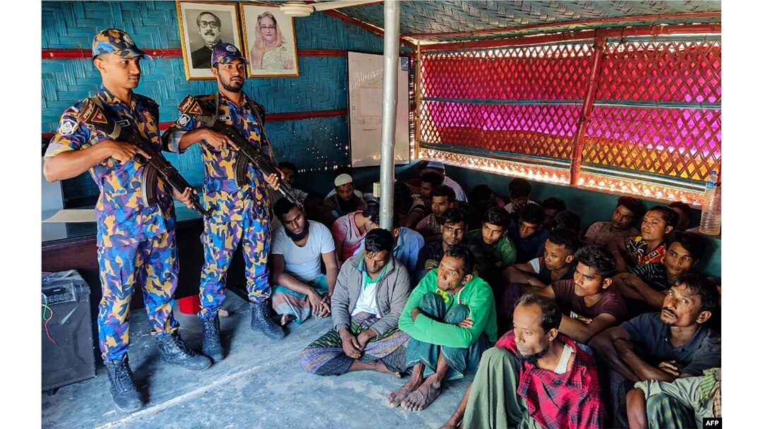 FILE - Detained Rohingya refugees sit next to security personal after crackdown in Rohingya refugee camp in Ukhia, Oct. 28, 2022. (AFP photo / Bangladesh Armed Police Battalion)